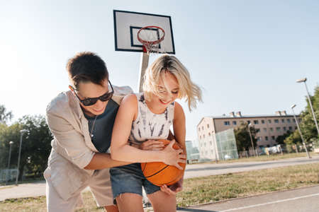 happy couple playing on basketball on playgroundの写真素材
