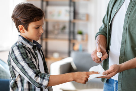 father treats sons injured finger with antisepticの写真素材