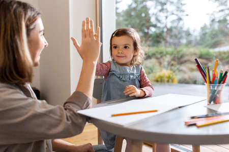 mother with daughter drawing and making high five