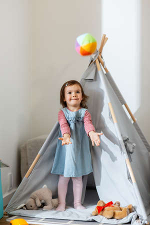 baby girl playing with ball in teepee at home