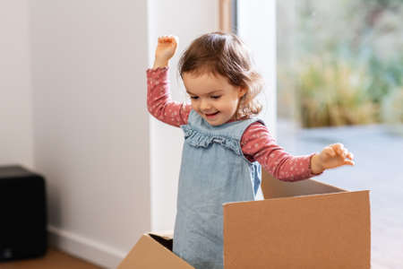 baby girl playing with cardboard box at home