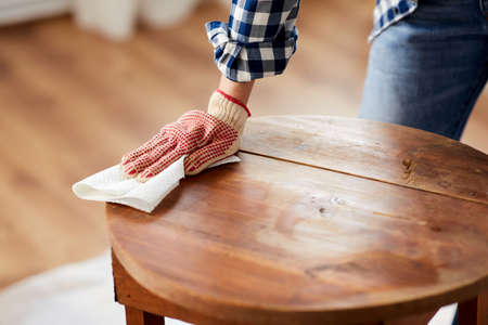 woman cleaning old table surface with paper tissue