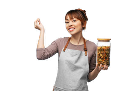 smiling woman in apron holding jar with pasta