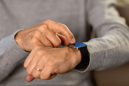 close up of senior man hands with smartwatch