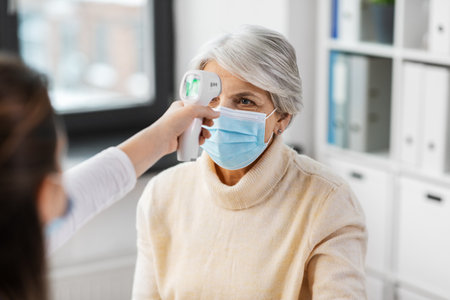doctor with thermometer and woman at hospitalの写真素材