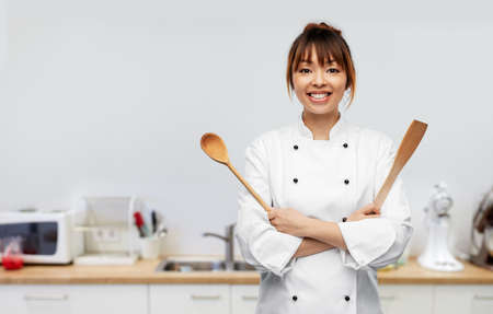 happy female chef with wooden spoon on kitchen