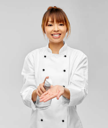 female chef applying hand sanitizer or liquid soapの写真素材