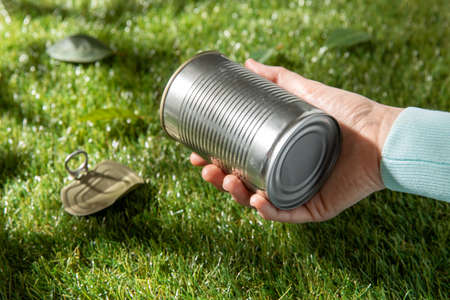 close up of hand removing used tin can from grassの写真素材