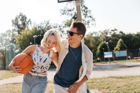 happy couple with ball on basketball playgroundの写真素材