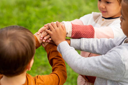 group of children stacking hands at parkの写真素材