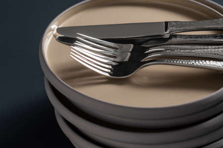 ceramic plates, forks and knives on black tableの写真素材
