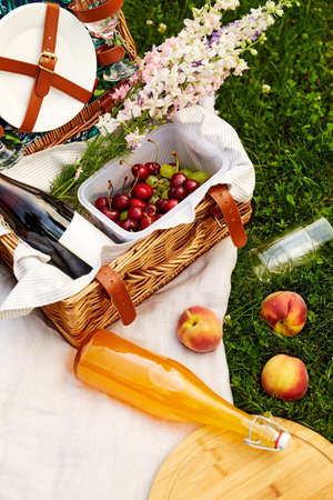 food, drinks and basket on picnic blanket on grassの写真素材