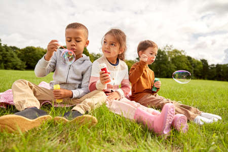 group of children blowing soap bubbles at park