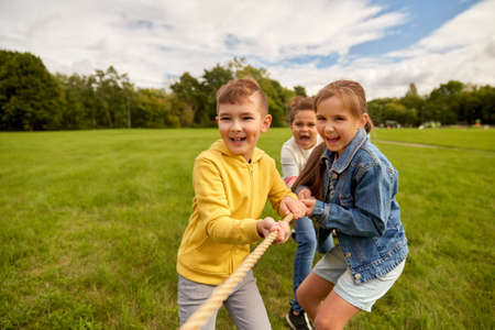happy children playing tug-of-war game at parkの写真素材