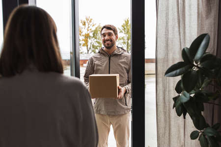 delivery man with parcel box and customer at home