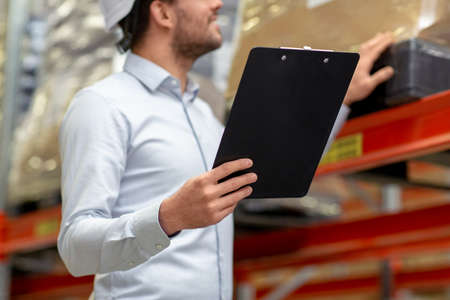 businessman in helmet with clipboard at warehouse