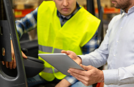 men with tablet pc and forklift at warehouse
