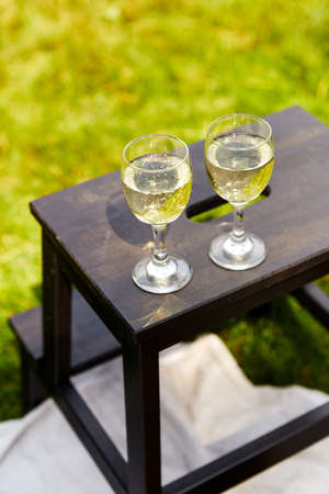 close up of glasses of champagne on stool at park