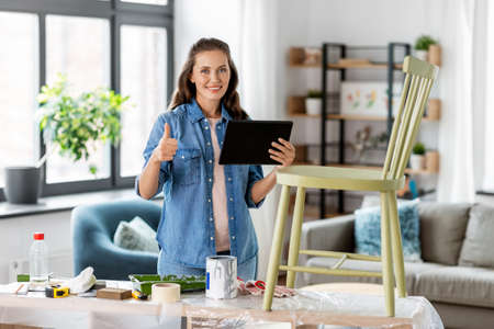 woman with tablet pc and old chair shows thumbs up