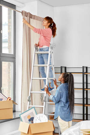 woman on ladder hanging curtains at homeの写真素材