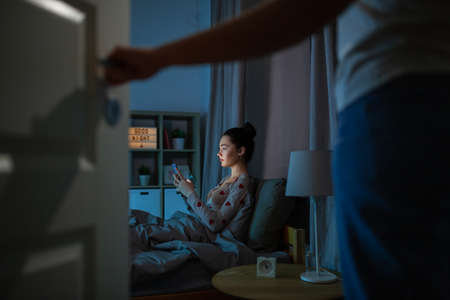 teenage girl with tablet pc in bed at nightの写真素材