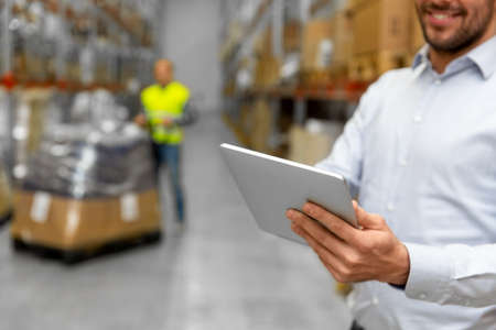 happy businessman with tablet pc at warehouse