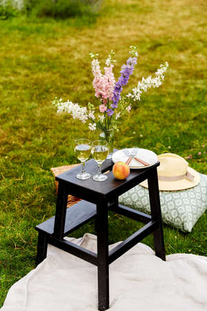 picnic basket, flowers and wine glasses at park