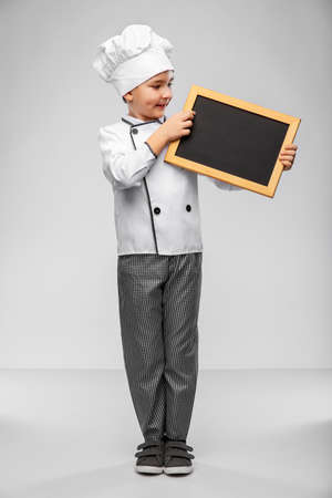 happy little boy in chefs toque with chalkboardの写真素材