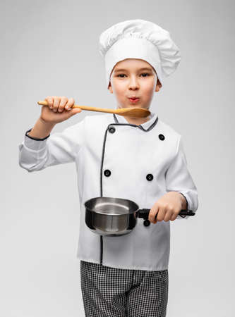 boy in chefs toque with saucepan cooking foodの写真素材