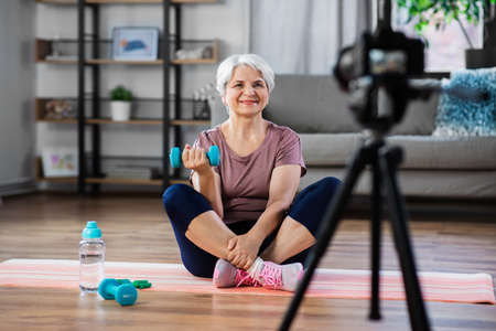 woman or fitness blogger with camera at home