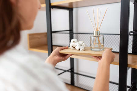 woman placing aroma reed diffuser to shelf home