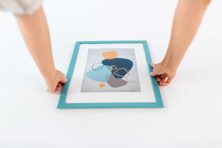 close up of hands hanging picture in frame on wall