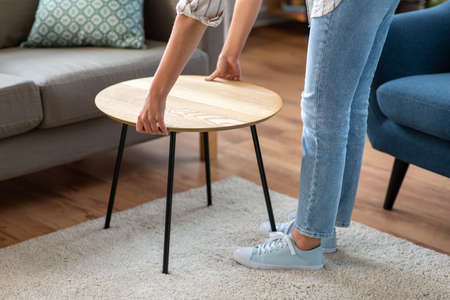 woman placing coffee table next to sofa at home