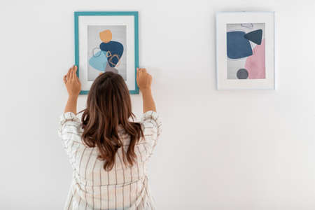 woman decorating home with picture in frame