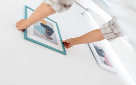 close up of hands hanging picture in frame on wall