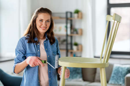 woman painting old chair in grey color at home