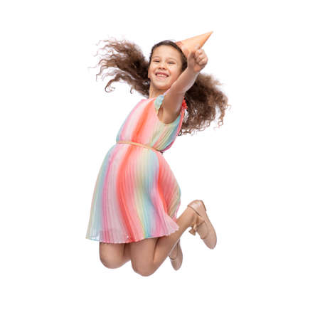 smiling little girl in birthday party hat jumpingの写真素材