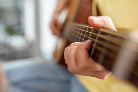 close up of man playing guitar sitting on sillの写真素材