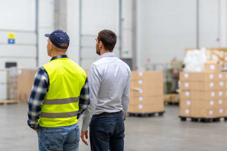 worker and businessman walking along warehouse