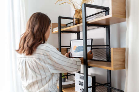 woman decorating home with picture in frame