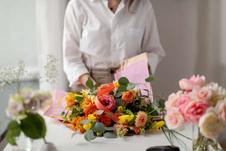 woman wrapping flowers to craft paper at studioの写真素材