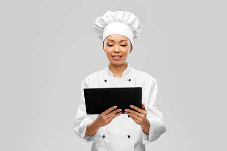 smiling female chef with tablet computerの写真素材