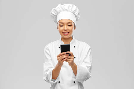 smiling female chef with smartphoneの写真素材