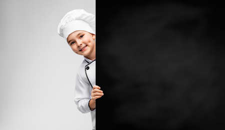 happy little boy in chefs toque with chalkboardの写真素材