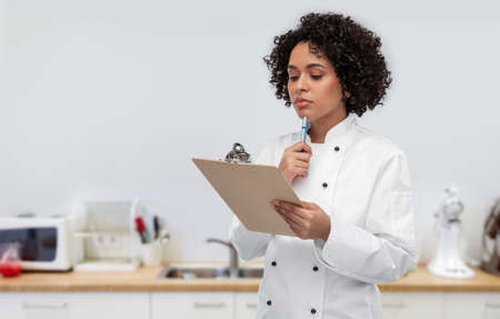 thinking female chef with clipboard and penの写真素材