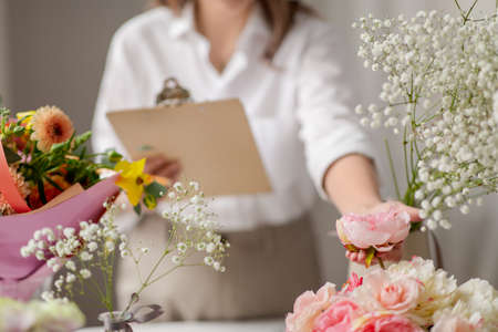 happy woman with clipboard and flowers at studioの写真素材
