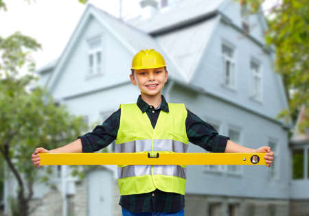 boy in construction helmet and vest with level