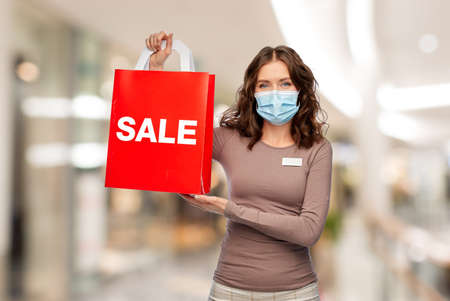 saleswoman in mask with word sale on shopping bagの写真素材