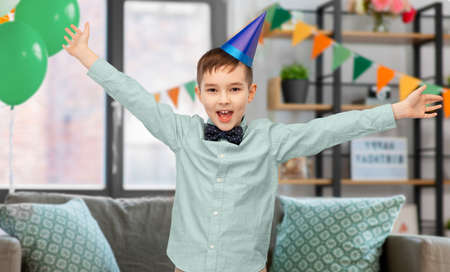 happy little boy in birthday party hat at homeの写真素材