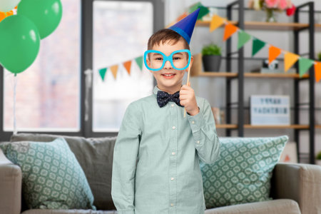 boy in birthday party hat with glasses at homeの写真素材